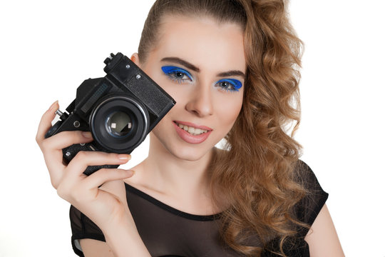 Young beautiful girl with makeup and haircut with a camera in her hand isolated on white background. Studio photography.