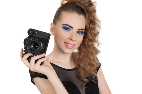 Young beautiful girl with makeup and haircut with a camera in her hand isolated on white background. Studio photography.