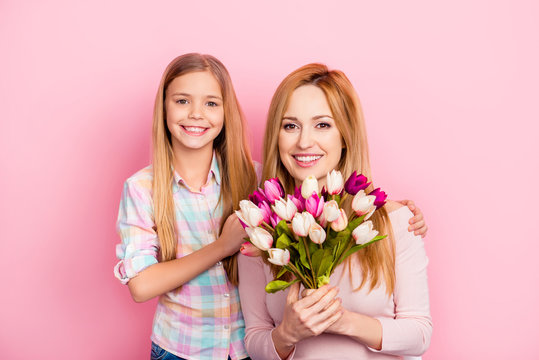 Pretty, lovely, nice, mum and daughter with beaming smiles celebrating women's day, standing over pink background, holding colorful tulips, looking at camera, leisure, happiness, fun, trust