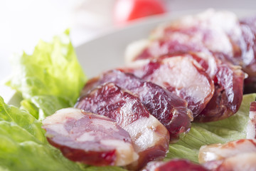 Close-up of cold cuts and vegetables on a plate. Raw pork sausage.