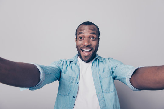 Hi guys! Portrait of adorable excited amazed funny joyful african man taking self portrait while having a trip around the world isolated on gray background