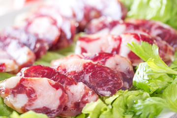 Close-up of cold cuts and vegetables on a plate. Raw pork sausage.