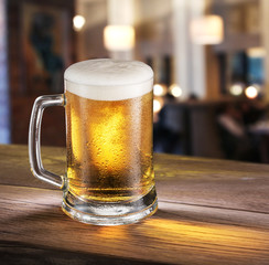 Frosty glass of light beer on the bar counter.