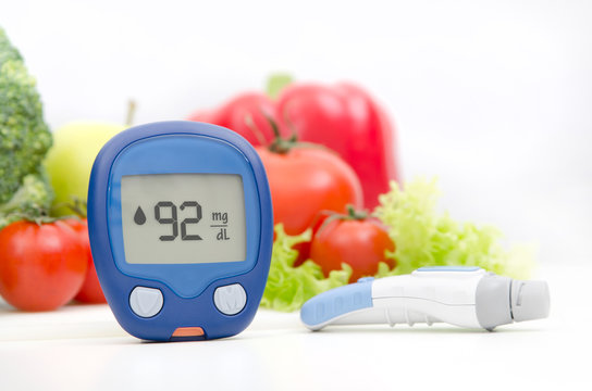 Glucometer and lancelet on vegetables background