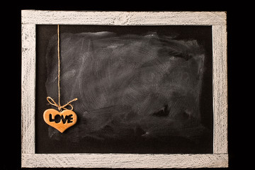 wooden heart on blackboard in room on black background