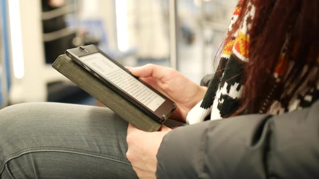 Young woman read e-book in subway train at metro