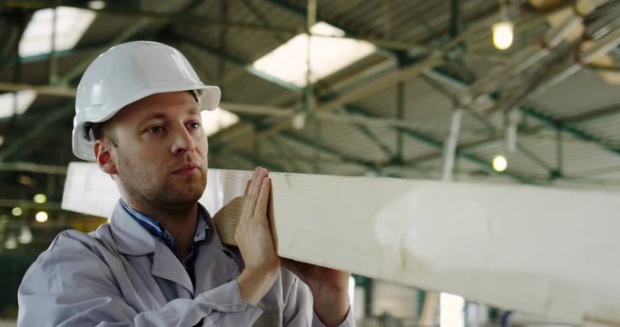 Carpenter carrying a big long planch in a woodfactory. Indoor. Close up. Portrait shot