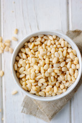 Pine nuts in a ceramic bowl over wooden table.