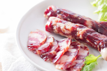 Close-up of cold cuts and vegetables on a plate. Raw pork sausage.