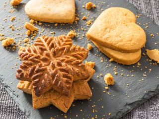 Yellow ginger biscuits in the shape of snowflakes and hearts on a black background