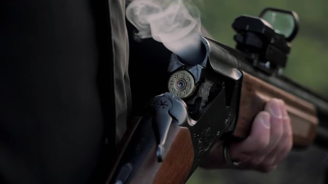 Smoke from the trunks of smooth-bore hunting rifle after firing. Hunter takes out cartridges from a gun.