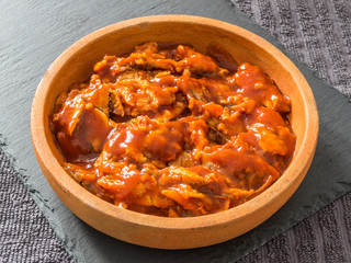 Sprat in tomato sauce in a ceramic saucer on a black background. Canned fish.