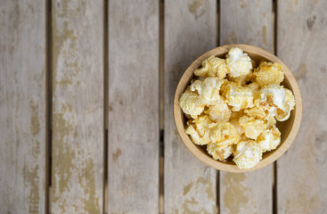 Salted popcorn in round wooden bowl with space on wooden table background, movie night snack