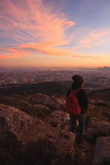 Fototapeta premium Girl watching beautiful sunset and city from mountain top