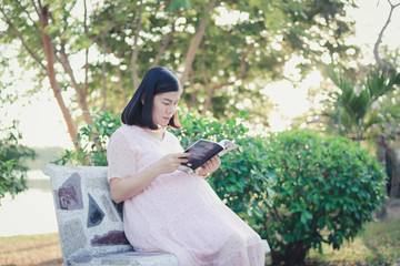 Fototapeta premium Pregnant woman sitting on a bench in park.