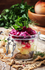 Traditional Russian salad with herring and vegetables, vintage wooden background, selective focus