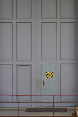 Big industrial door, with warning sign: crushing hazard by crane