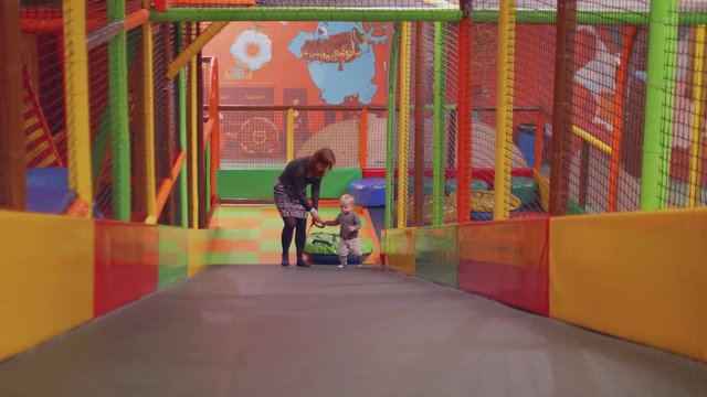 Red haired mom and blond son climb slide dagging tube