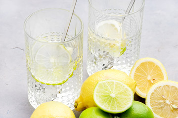 Fototapeta na wymiar Lemonade With Citrus Lemon and Lime Detox Healthy Water Summer Cold Drink Ice Cubes Wooden Squeezer Glasses