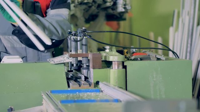 A worker operates a rotary saw for small plastic profiles. 