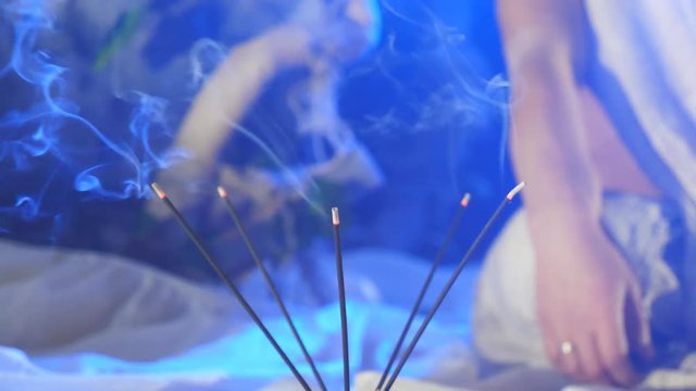 Incense smoke from soothing sticks on a blue background. Calm and relax concept. Aromatherapy with cleansing incense smoke. Close up Slow motion