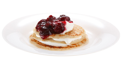 Serving pancakes with sour cream and cherry jam on the plate. Isolated on white background.