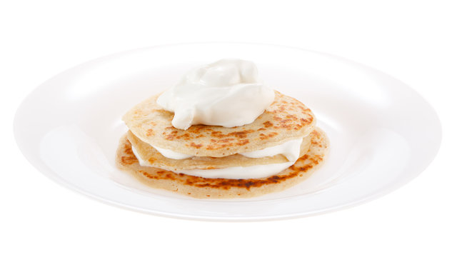 Serving pancakes with sour cream on the plate. Isolated on white background.