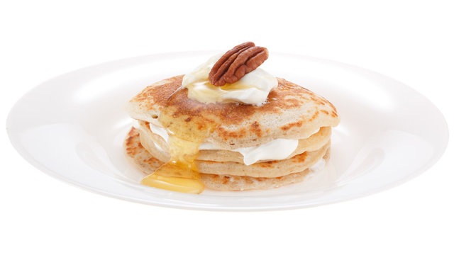 Serving pancakes with sour cream honey and nut on the plate. Isolated on white background.