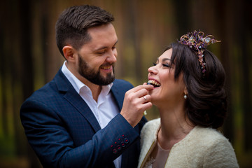 portrait of  groom feeding bride  berry in forest