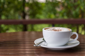 Cappuccino cup on wooden table with bokeh view