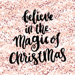 Inscription Believe in the Magic of Christmas, on a pink gold glitter background. It can be used for card, mug, brochures, poster, t-shirts, phone case etc.