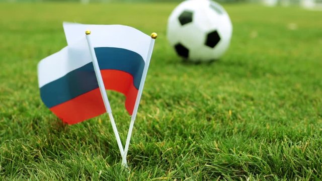 Flags of the Russian Federation on green grass and a football ball. Flag of Russia and soccer ball.
