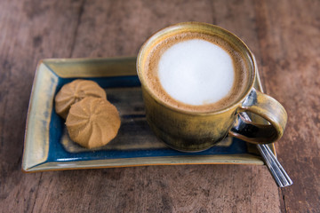 Cappuccino cup with cookies on wooden table