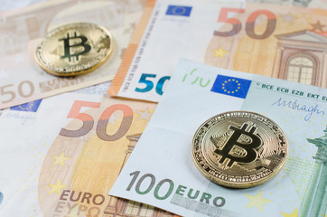 Two golden bitcoins on Euro banknotes.