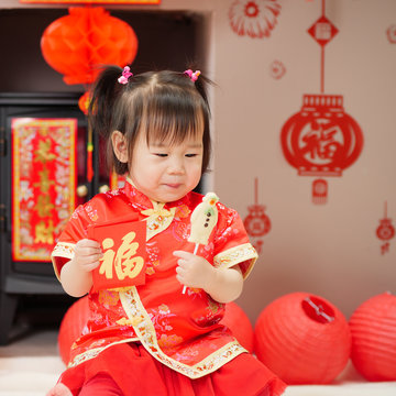 Chinese baby girl  traditional dressing up with a "FU" means" lucky "red envelope