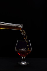 Whiskey poured into low glass on black background.