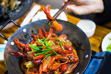 Chopsticks taking crayfish from spicy crayfish pot