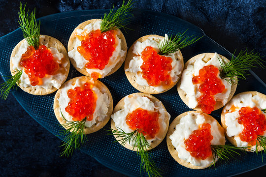 appetizer of red caviar and cheese with dill in a plate in the shape of a fish on a blue background