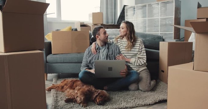 Loving girl hugging boyfriend. Young people and dog resting at home on weekends.