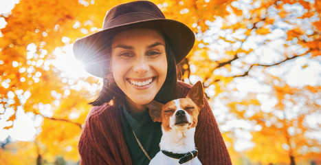 Portrait of happy young woman with dog outdoors in autumn