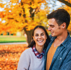 Portrait of smiling young couple outdoors in park in autumn