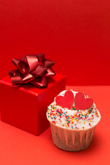 cute cupcakes and gift box with bow  on a red background