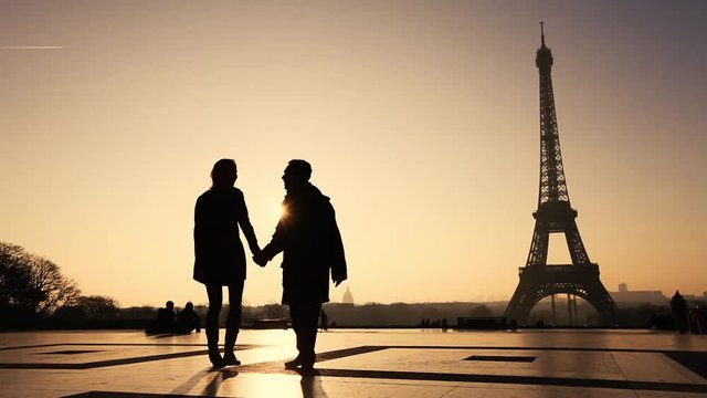 happy affectionate couple in Paris near Eiffel tower, silhouettes of man and woman on honeymoon in Europe