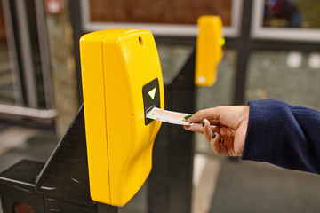 Woman punching ticket in validating machine device to entering at metro station in Prague