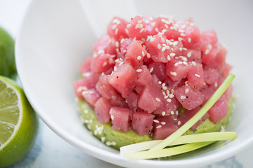 Closeup of tuna tartar with sesame seeds on guacamole bedding, selective focus