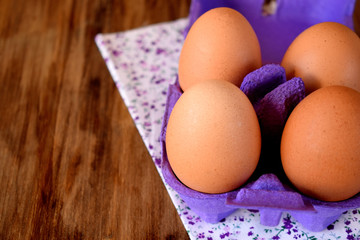 Chicken eggs in a carton box on a wooden table