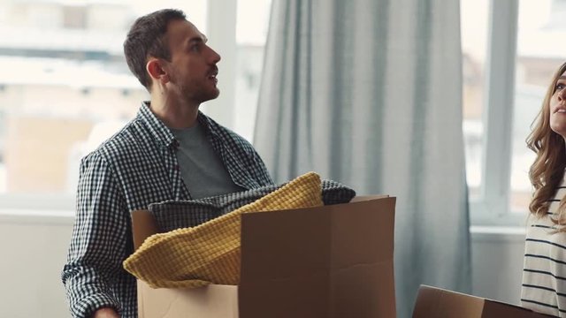 Young Attractive Caucasian newlyweds moving stuff in new apartment. Things of owners packing in big and small boxes. Indoor.