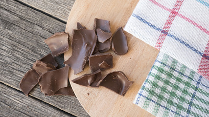 Fototapeta na wymiar Crushed dark chocolate on old wooden table