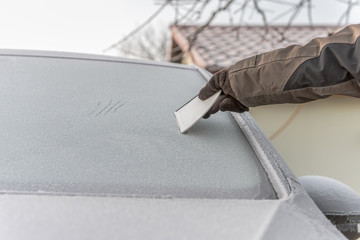 Scraping ice from frozen car windshield or side window. Closeup of scraping with a ice scraper....