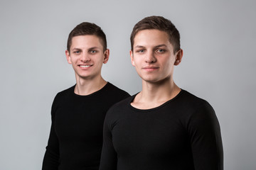 The two twin brother stand on the gray background